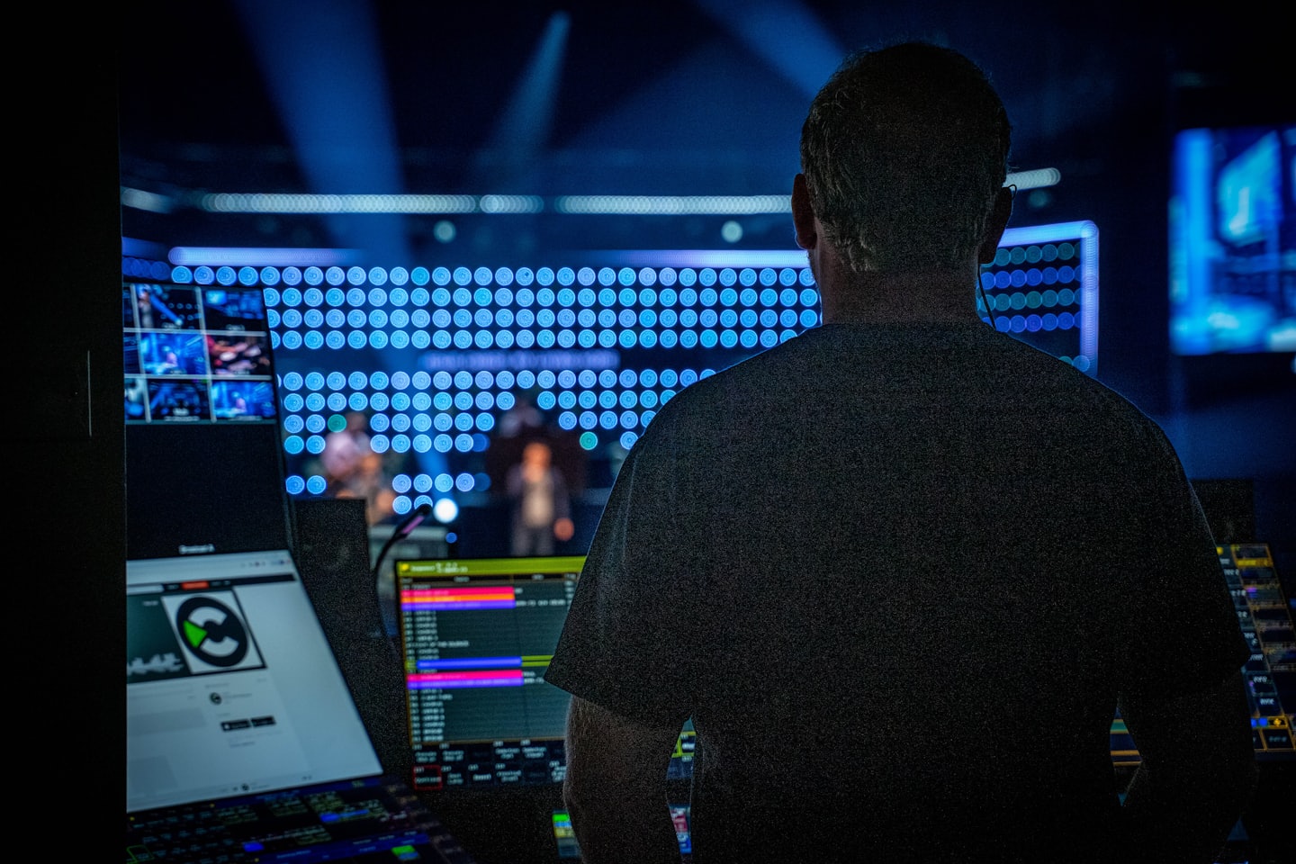 Technician operating a complex control desk with glowing screens.