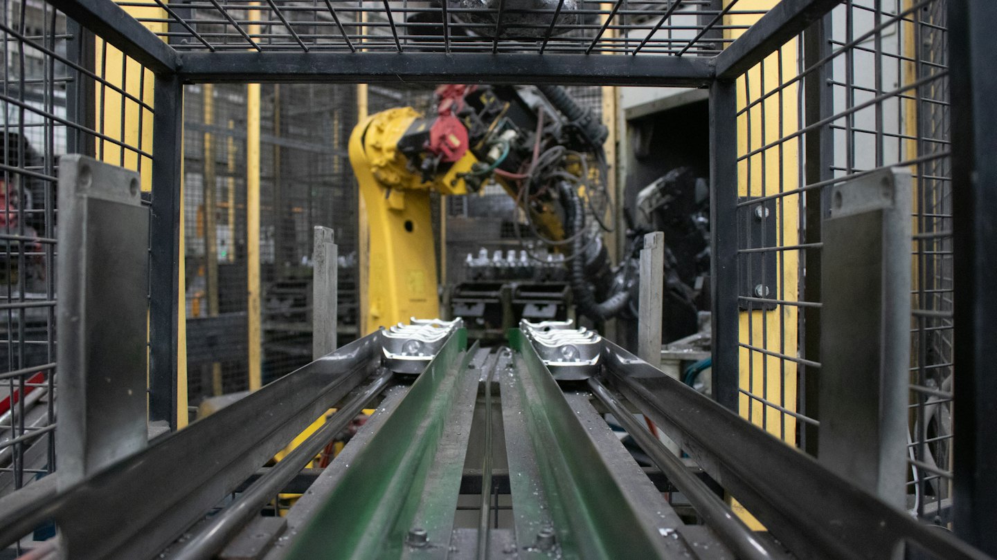 Robotic arm works on production line with conveyor belts.